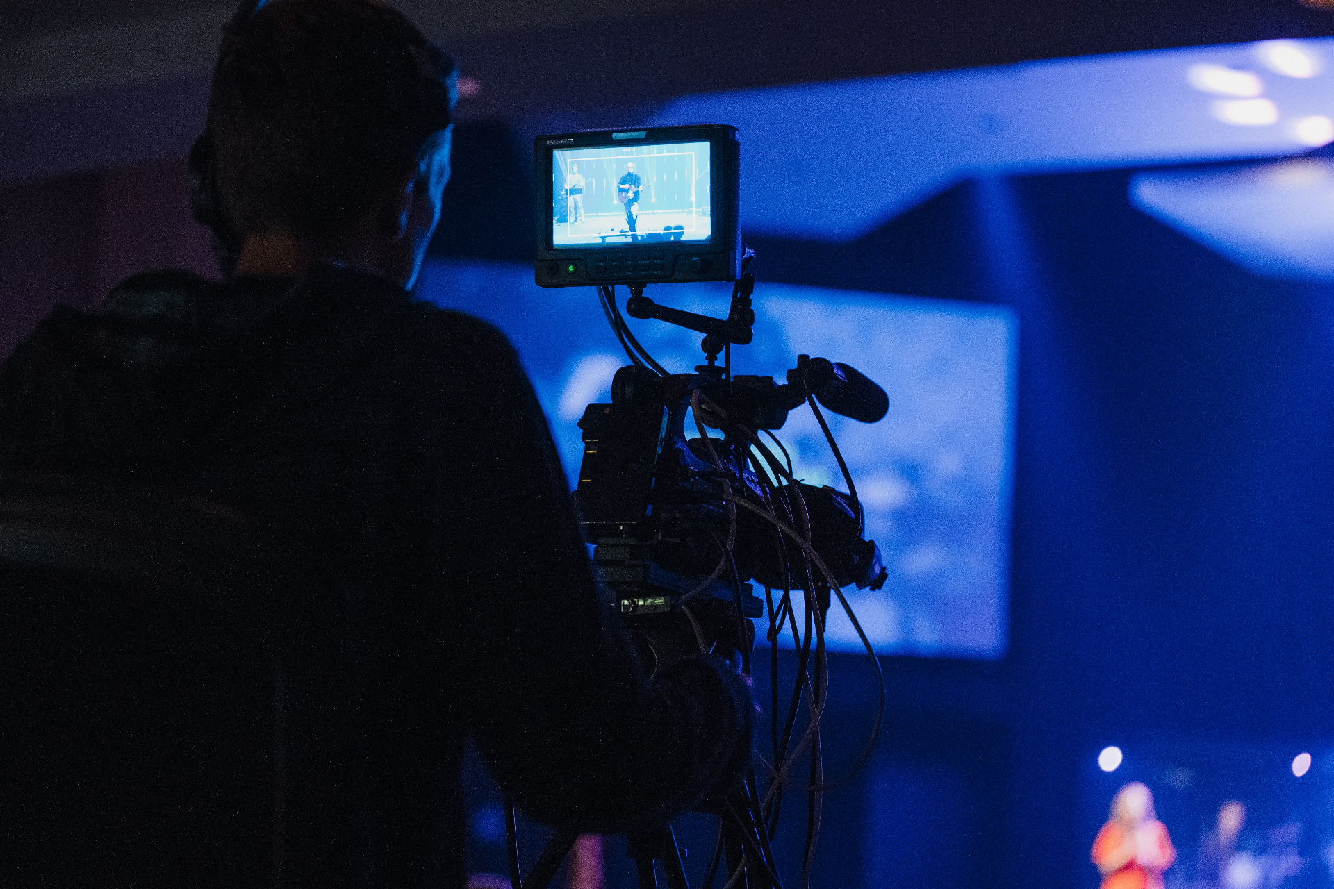Videographer operating a camera at a church service with stage lights in the background