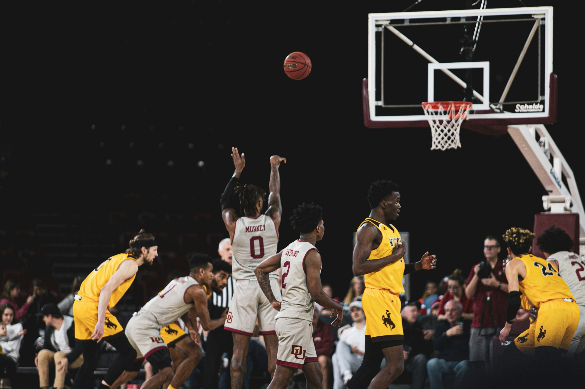 A college basketball player shooting a free throw during a game, with teammates and opponents lined up along the lane